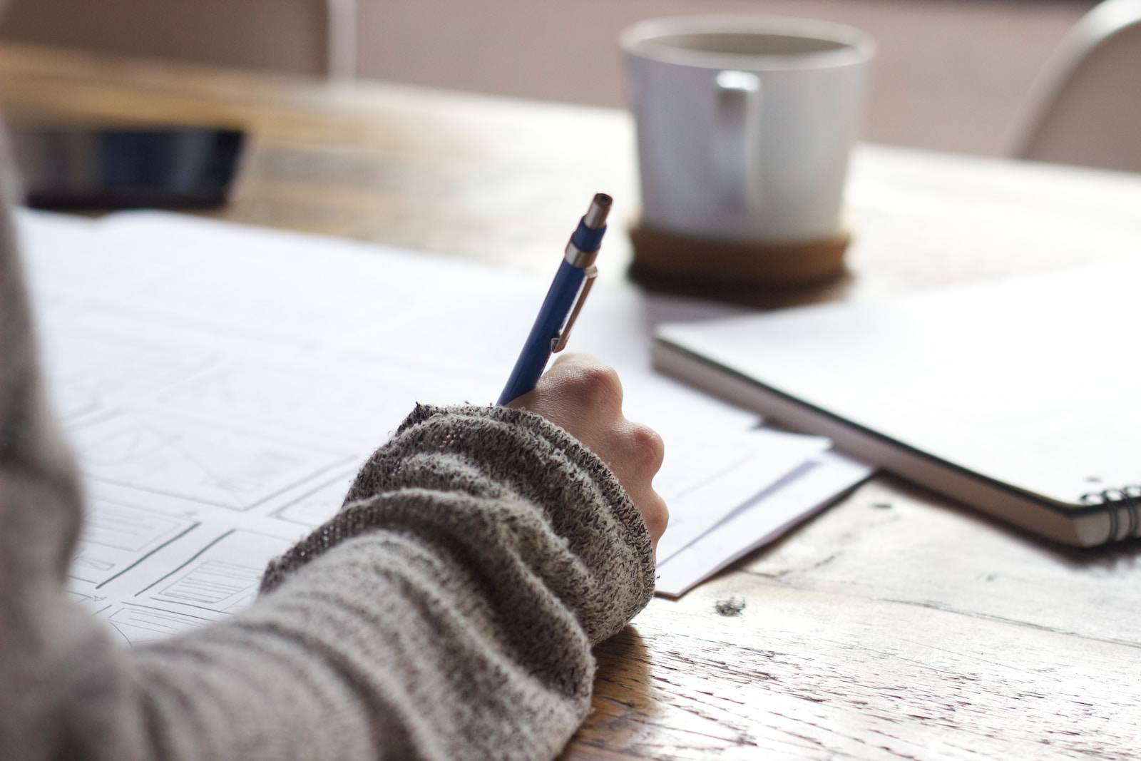 content marketing person writing on brown wooden table near white ceramic mug